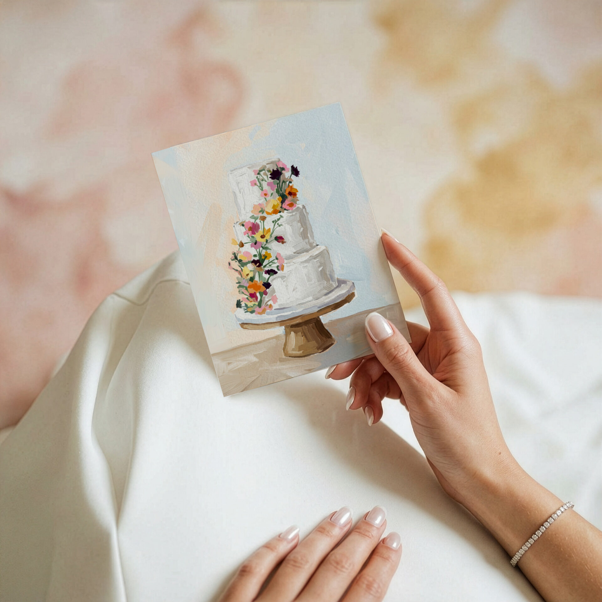 Carte de souhait illustrée « Gâteau fleuri » de Mimosa Design, représentant un gâteau de mariage à quatre étages décoré de fleurs sauvages colorées, tenue à la main.